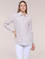 Camisa de calce relajado color celeste, confeccionada en tejido de textura suave y fluida. Presenta cuello camisero y abotonadura frontal, mangas largas con puño ancho y ruedo curvo.