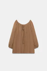 Blusa de lino color marrón con escote recto ajustable mediante cordones, hombros descubiertos y mangas largas abullonadas con puños elásticos.