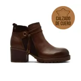 Bota corta de cuero color marrón con paneles laterales en gamuza, taco cuadrado de madera y suela track dentada. Presenta un detalle de cordón decorativo con herrajes metálicos en el tobillo.