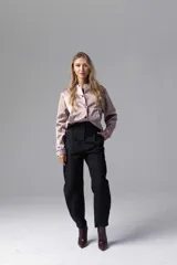 Pantalón negro de tiro alto, corte holgado, con pinzas, bolsillos cargo laterales y ajuste con botones en el ruedo.