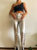 Pantalón plateado de corte recto con aberturas en el ruedo.