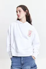 Canguro blanco de felpa con capucha ajustable, bolsillos frontales tipo canguro y estampado en frente y espalda.