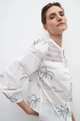 Camisa blanca estampada con palmeras y bordados en azul.