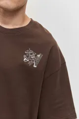 Remera marrón oversize de manga corta, con cuello redondo y pequeños estampados blancos en el pecho.
