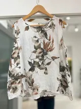 Musculosa blanca de lino con estampado floral en tonos marrones y verdes, cuello redondo y diseño sin mangas.