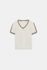 Camiseta slim fit de hilatura con algodón, color blanco roto con ribetes marrones en el escote en pico y en las mangas cortas.