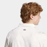 Remera polo Adidas de manga corta, color blanco con cuello tipo polo y estampado frontal con el texto "Originals" en estilo gráfico deportivo.