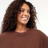 Sweater de punto calado color marrón, de mangas cortas y cuello redondo, con diseño holgado y detalle de nudo en el frente.