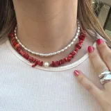 Collar corto doble, uno con perlas pequeñas y otro con piedras rojas irregulares y una perla central.