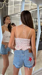 Short de jean tiro bajo con diseño de estrella roja aplicada en el bolsillo trasero y terminación desmechada en las piernas.