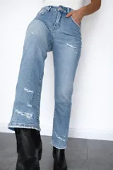 Pantalón de jean corte regular fit en color celeste claro. Presenta un diseño con pequeñas roturas frontales y botamanga con doblez, confeccionado en denim con elastano para mayor flexibilidad y comodidad.