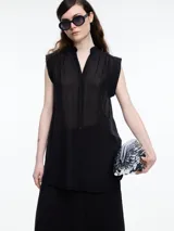 Camisa negra sin mangas con cuello mao y cierre frontal con botones.