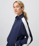 Campera deportiva de microfibra azul marino con cuello alto, cierre frontal y franjas blancas en contraste a lo largo de las mangas.