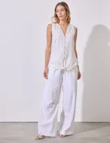 Blusa sin mangas de lino y rayón a rayas verticales amarillas y celestes, con cuello a la base y escote en V, abertura central con botones y terminación anudada.