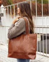 Bolso tipo tote de cuero vacuno, color marrón, con textura efecto reptil en la parte superior y base de cuero liso. Cuenta con doble asa de hombro y cierre superior.