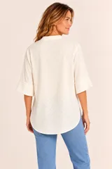 Blusa de algodón color beige con diseño texturizado, cuello mao con escote en V, mangas tres cuartos y dobladillo asimétrico más largo en la parte trasera.