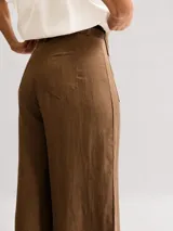 Pantalón blanco de tiro alto y corte amplio, confeccionado en Tencel y lino. Cuenta con bolsillos frontales tipo parche con solapa y un cinturón negro delgado incorporado.