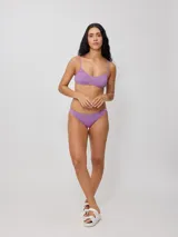 Top de bikini con tirantes finos y escote redondo, confeccionado en poliamida con elastano, con estampado tropical en tonos verdes, celestes y salmón sobre fondo negro.