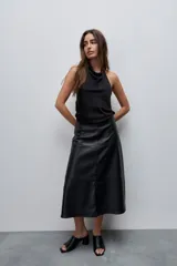 Falda midi de efecto cuero color negro, con corte evasé, tiro alto y diseño con recortes horizontales. Posee cierre lateral oculto.