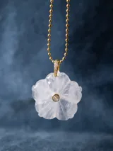 Collar con cadena de eslabones tipo bolita dorada y dije de piedra natural tallada en forma de flor con una pequeña circonia incrustada en el centro.