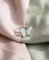 Anillo de acero con diseño de mariposa y apliques de nácar, con banda texturizada de pequeñas esferas.