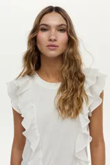 Blusa blanca vaporosa con volados en los hombros y cuello redondo.