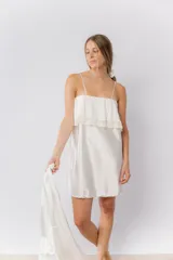 Camisón corto de satén elastizado color blanco, con escote recto y detalle de volado con puntilla en el pecho. Posee breteles finos regulables.