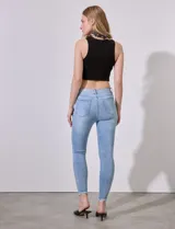 Jean skinny celeste con roturas en las rodillas y terminación desflecada.