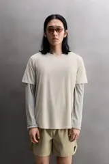 Camiseta de entrenamiento regular fit color beige, confeccionada en combinación de tejidos técnicos ligeros y elásticos con tecnología Quick Dry nivel 2. Presenta cuello redondo, manga corta, acabados con costuras planas y termofijadas, y detalle de logo estampado en el bajo.