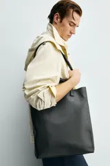 Bolso tipo shopper de diseño minimalista, confeccionado en piel con acabado abatanado. Cuenta con doble asa de mano y doble asa de hombro, compartimento principal amplio sin cierre y bolsillo interior plano.