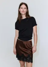 Minifalda marrón satinada con estampado de lunares negros y detalle de puntilla de encaje negro en el ruedo.