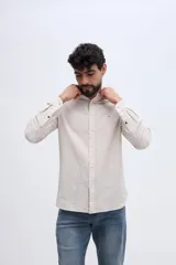 Camisa de lino y algodón color celeste, con cuello mao, cierre frontal de botones claros y pequeño bordado de pato en el pecho.