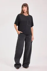 Remera negra de corte recto con cuello redondo y bolsillo en el pecho. Detalles de tachas plateadas en cuello, mangas y bolsillo.