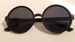 Lentes de sol redondos con montura de plástico color negro y cristales grises.