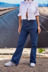 Jean de tiro bajo y corte oversize, confeccionado en denim azul con monograma grabado a láser en toda la prenda. Presenta doble botón metálico en la cintura y diseño de cinco bolsillos.