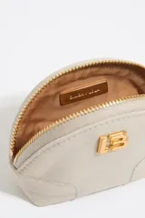 Monedero de nylon en color beige, con forma semicircular y cierre de cremallera. Presenta el logo metálico LB en la parte frontal.