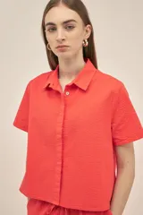 Camisa color coral de tejido seersucker texturizado, con cuello camisero, manga corta y cierre frontal con botones nacarados.
