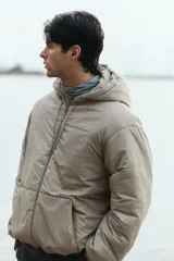 Campera acolchada de tejido funcional repelente al agua y rompevientos, color gris claro, de corte holgado con capucha ajustable, cierre frontal, bolsillos delanteros y puños elastizados.