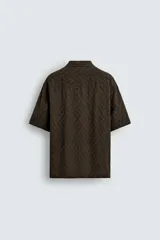 Camisa de corte relajado con cuello bowling y manga corta. Confeccionada en tejido fluido con textura jacquard de patrón geométrico y cierre frontal de botones.