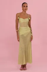 Vestido largo Patbo de color verde, confeccionado con un cuerpo de tejido tipo red transparente y detalles de tela lisa en el busto y cadera. Cuenta con breteles finos ajustables con detalles florales colgantes.