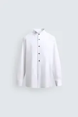 Camisa slim fit de algodón con cuello smoking, manga larga con puño doble para gemelos y pechera combinada a tono con cierre frontal de botones.