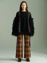 Sweater oversize de lana con diseño de trenza central, detalles en tejido cuadrillé y terminaciones desflecadas. Presenta mangas acampanadas, cuello a la base y aberturas laterales con tiras ajustables.