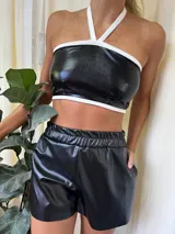 Top de cuerina negro con cuello halter y ribete blanco.