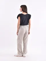 Pantalón marrón de corte ancho, con cintura elástica ajustable con cordón, bolsillos laterales y bolsillos tipo cargo en los muslos.