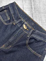 Pantalon jean de tiro alto con corte wide leg, confeccionado en denim azul oscuro con costuras en contraste. Presenta cierre frontal con botón metálico y bolsillos laterales.