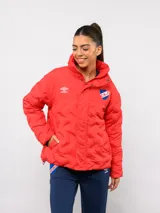 Campera puffer corta color rojo con cuello alto, cierre frontal con botones a presión y diseño acolchado. Presenta el logo de Umbro y el escudo del Club Nacional de Football bordados en el pecho.