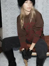 Buzo de tejido de punto grueso color marrón con diseño geométrico y floral estampado en color rojo. Presenta cuello redondo, mangas largas y puños y ruedo acanalados.