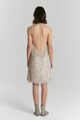 Vestido corto color beige con lentejuelas plateadas, de breteles finos y corte suelto.