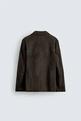 Blazer de corte relajado confeccionada en piel con acabado de ante. Presenta cuello con solapas de muesca, cierre frontal de dos botones, mangas largas y bolsillos de plastrón en la cadera. El diseño no posee forro interior y cuenta con aberturas en la parte trasera.