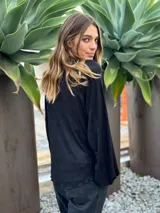 Blusa de manga larga color azul eléctrico con acabado brillante o metalizado, cuello alto y corte holgado.